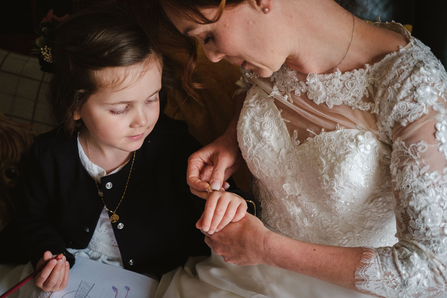 Bride helps put a bracelet on her daughter.